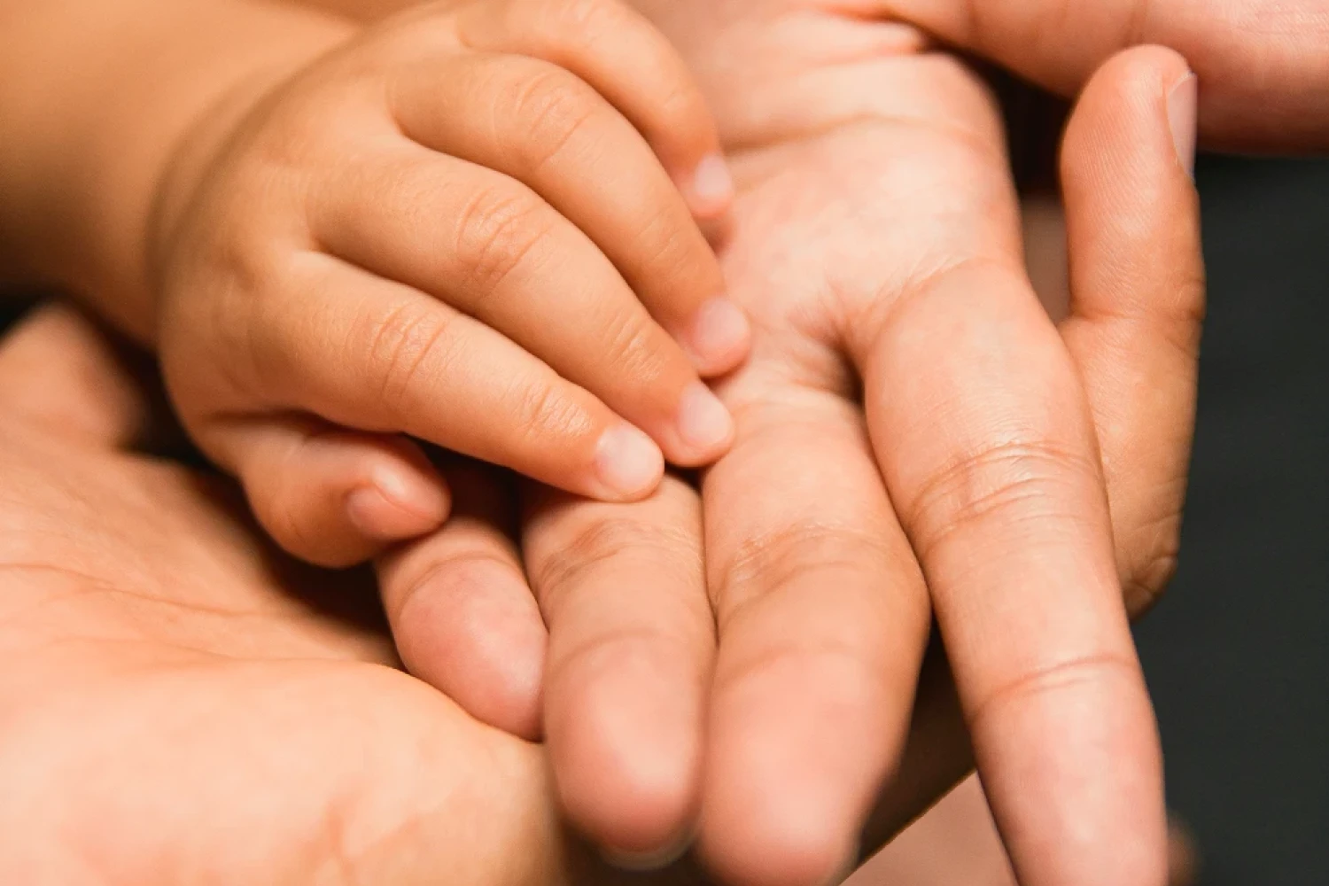 Zwei erwachsene Hände halten eine Kinderhand